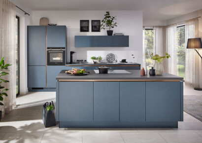 Stürzenberger Küchen – Moderne, blaue Küche mit Kochinsel und bronzefarbenen Kehlleisten.